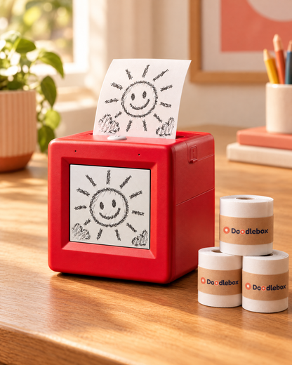Doodlebox printer printing a child's sunshine drawing with a stack of refill rolls
